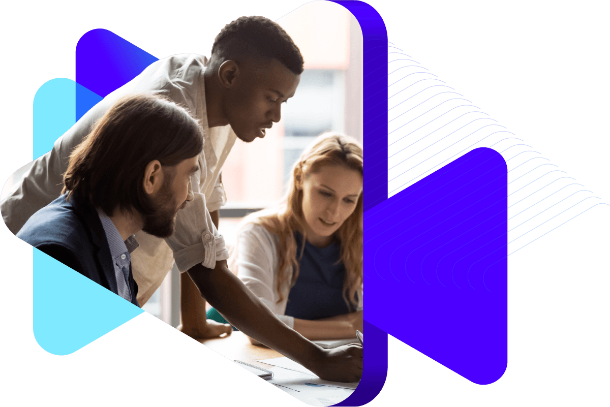 Three people having a discussion at a desk in an office.